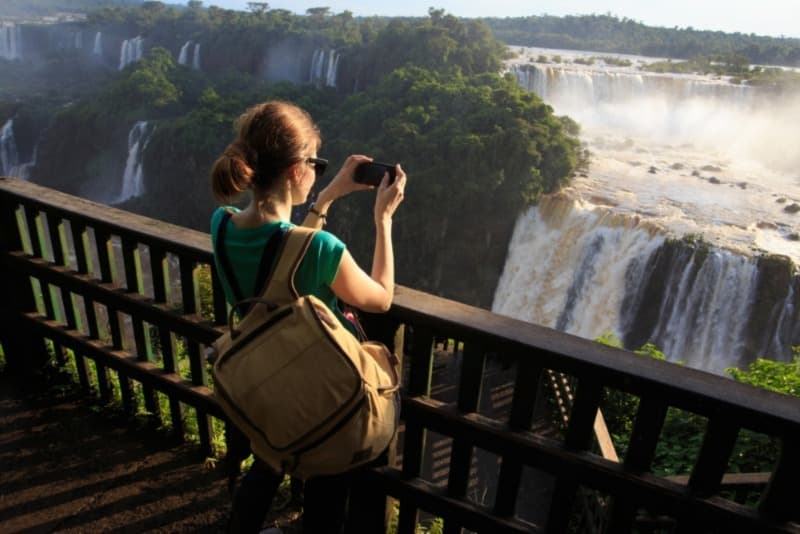 girl taking a photo of Iguassu waterfall with smartphone, Iguazu Falls